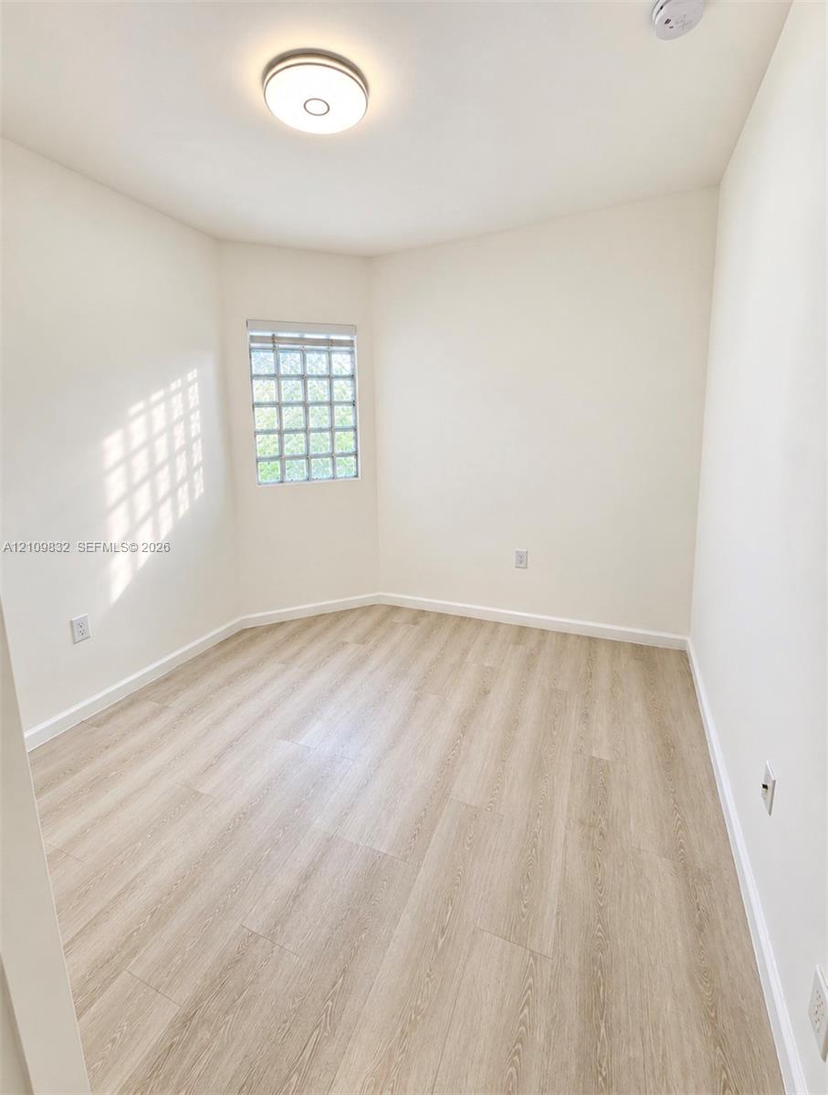Neutral-toned room featuring wood-finish flooring, glass block window, and circular flush-mount ceiling lighting