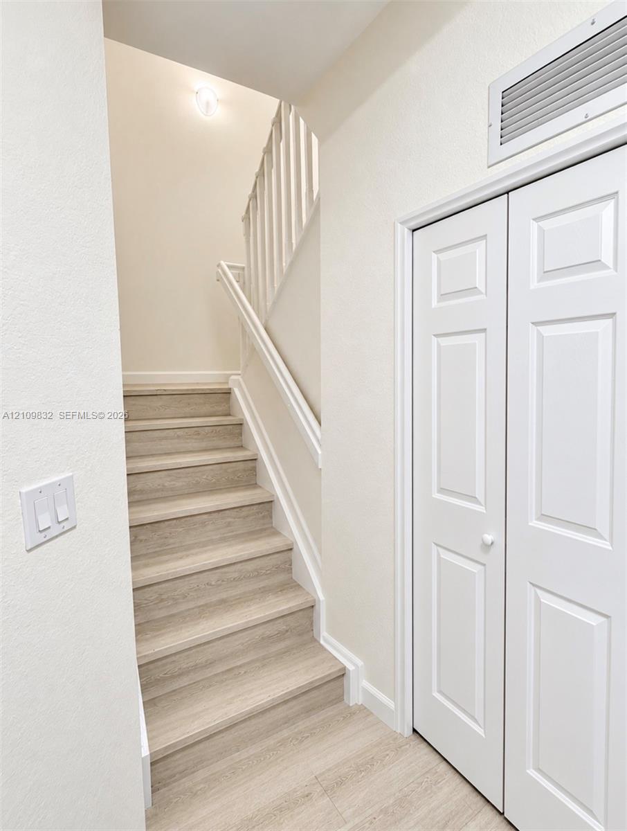 Staircase featuring wood-finish treads and a white wooden balustrade, paired with a white paneled bifold closet door Staircase featuring wood-finish treads and a white wooden balustrade, paired with a white paneled bifold closet door