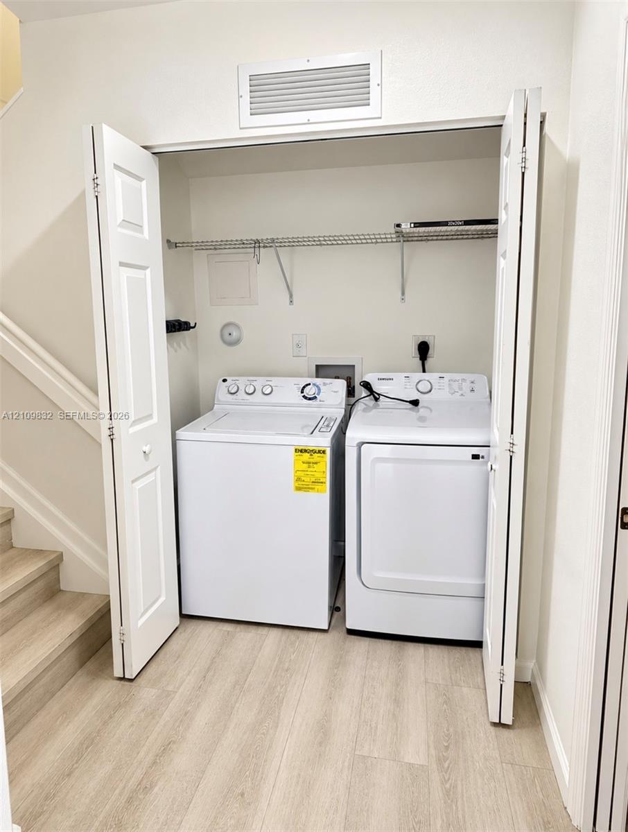 Laundry closet featuring bifold doors, wood-finish flooring, and wire shelving Laundry closet featuring bifold doors, wood-finish flooring, and wire shelving