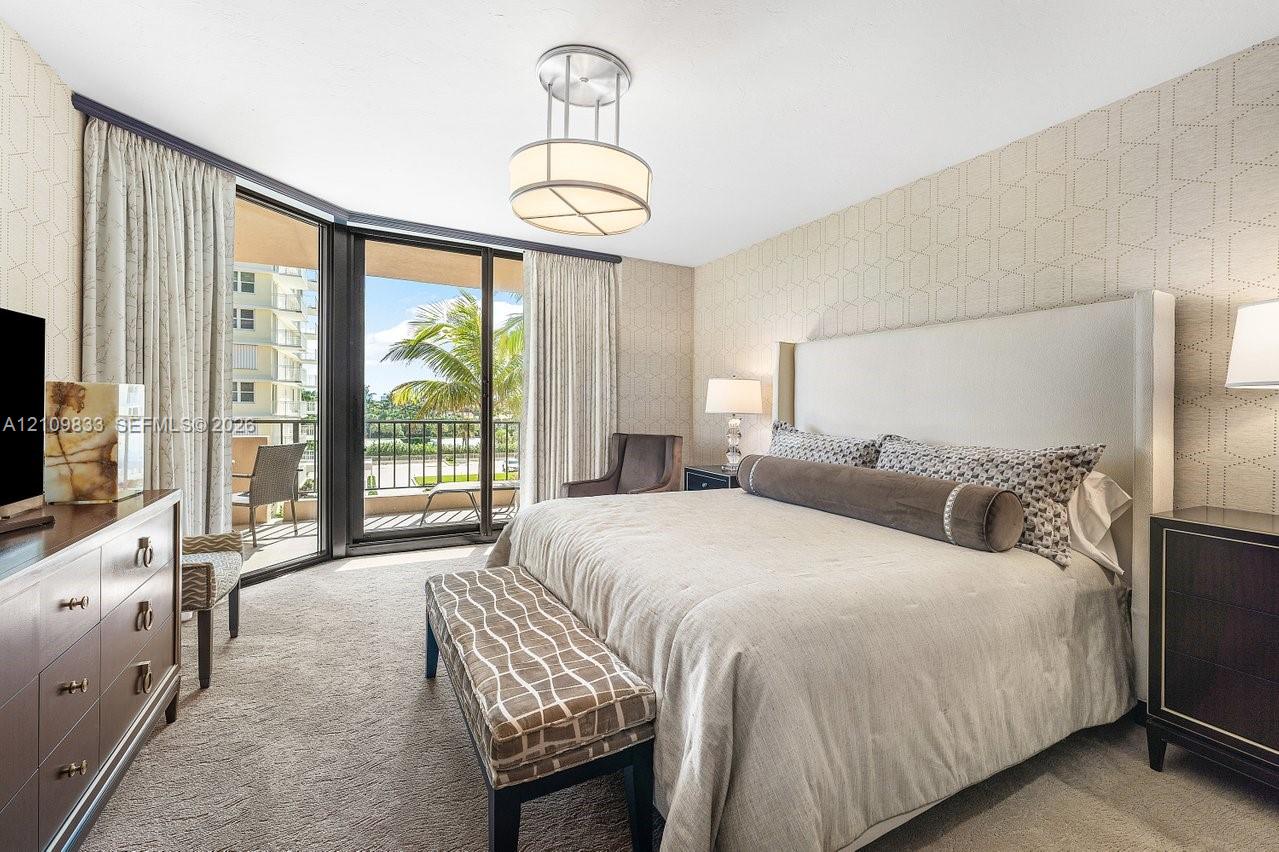 Floor-to-ceiling sliding glass doors, private balcony, patterned wall covering, carpeted flooring, and circular pendant lighting