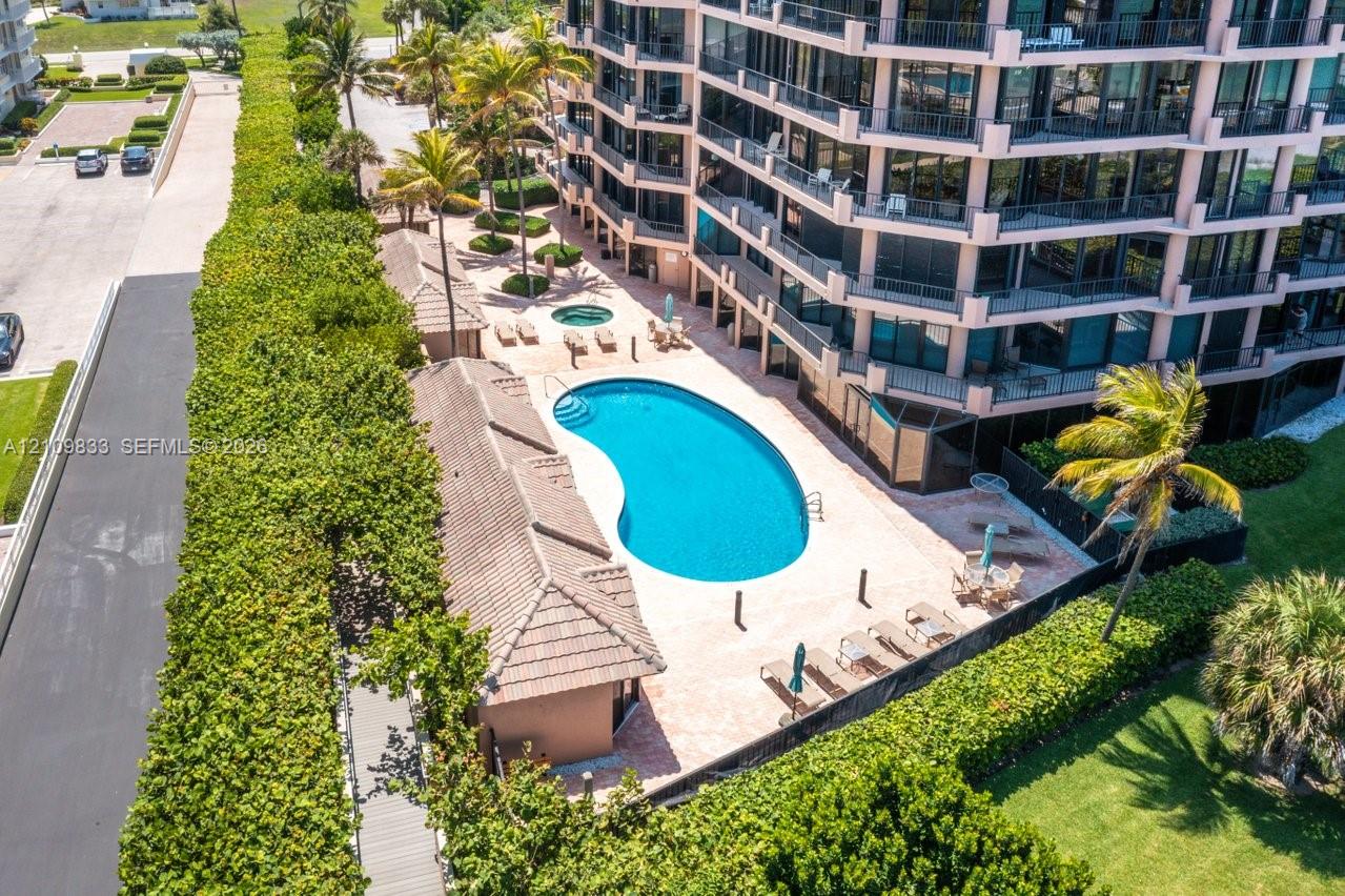 Multi-story high-rise featuring a kidney-shaped pool, separate spa, tile-roofed cabana, and manicured landscaping