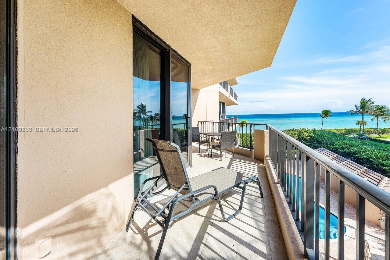 Covered balcony featuring tile flooring, metal railings, and sliding glass door entry