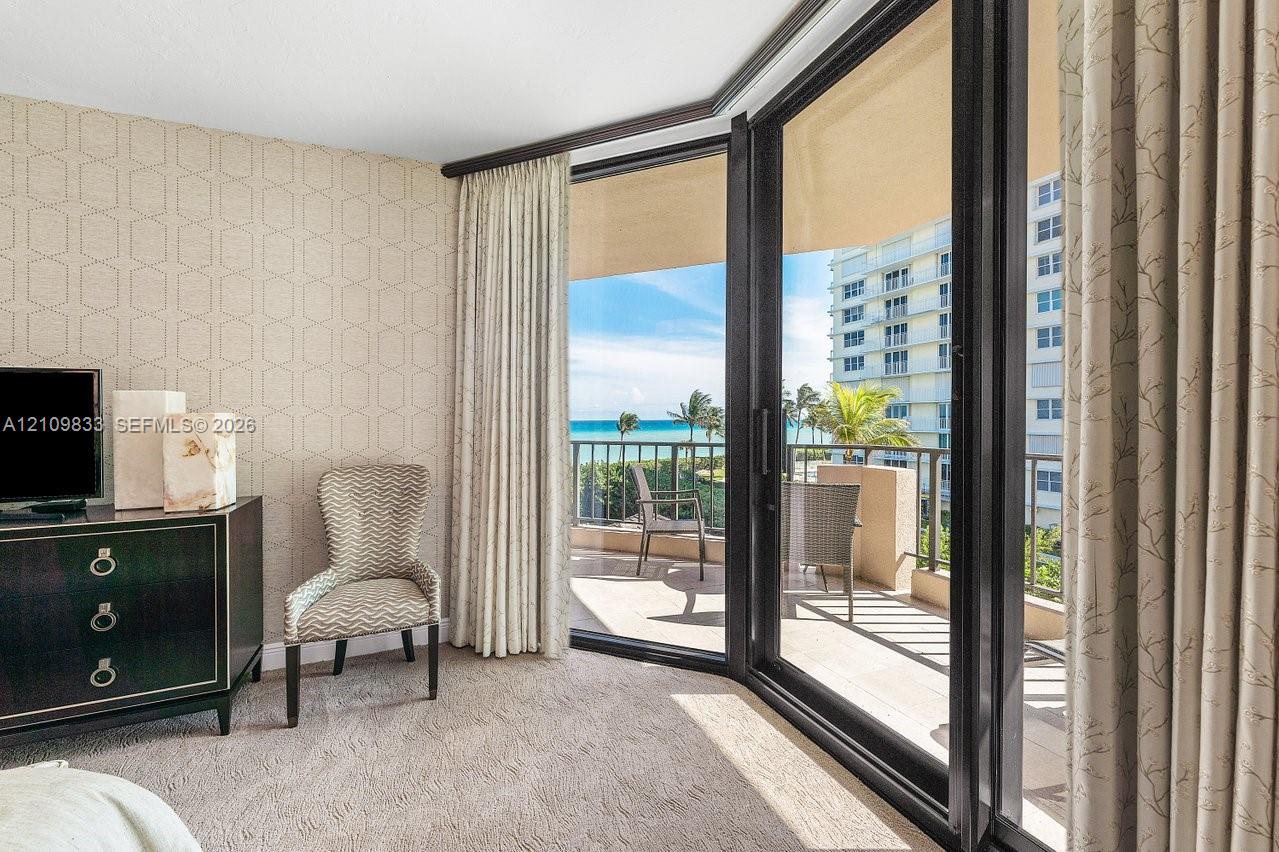 Floor-to-ceiling sliding glass doors, private balcony with metal railing, and patterned wall covering