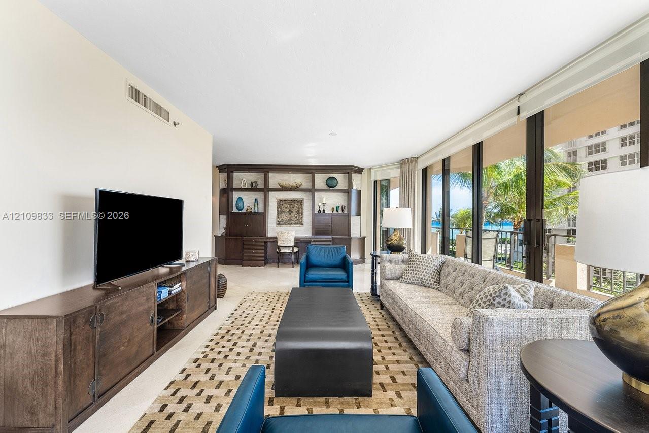 Living area featuring floor-to-ceiling glass sliding doors, built-in dark wood cabinetry, and neutral-toned flooring