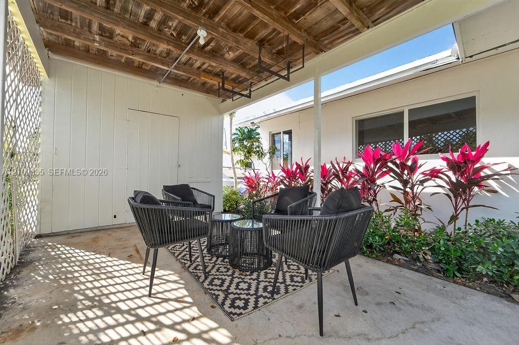 Covered patio featuring a concrete floor, wooden slat ceiling, lattice screen, and exterior wall cladding