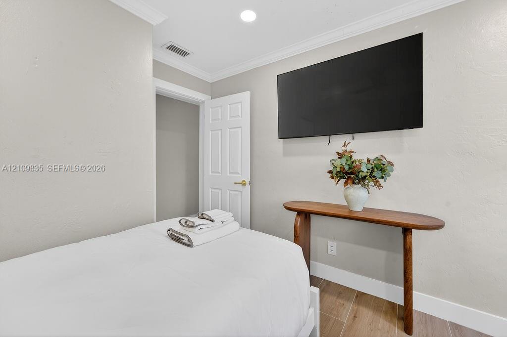 Neutral wall tones, wood-finish tile flooring, crown molding, and recessed lighting
