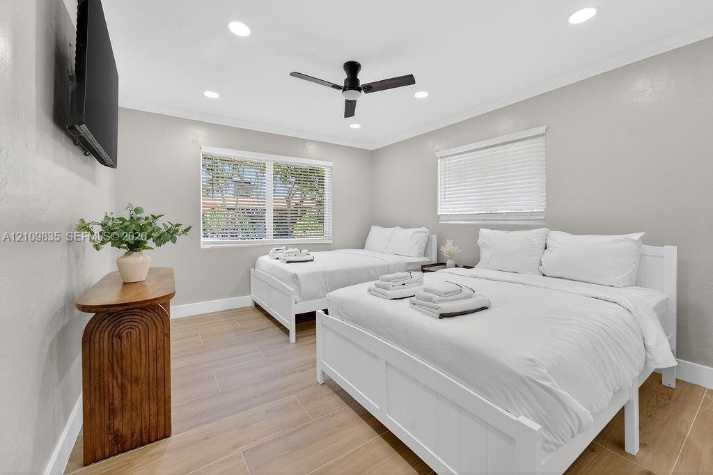Wood-finish flooring, recessed lighting, matte black ceiling fan, and dual windows with fitted blinds