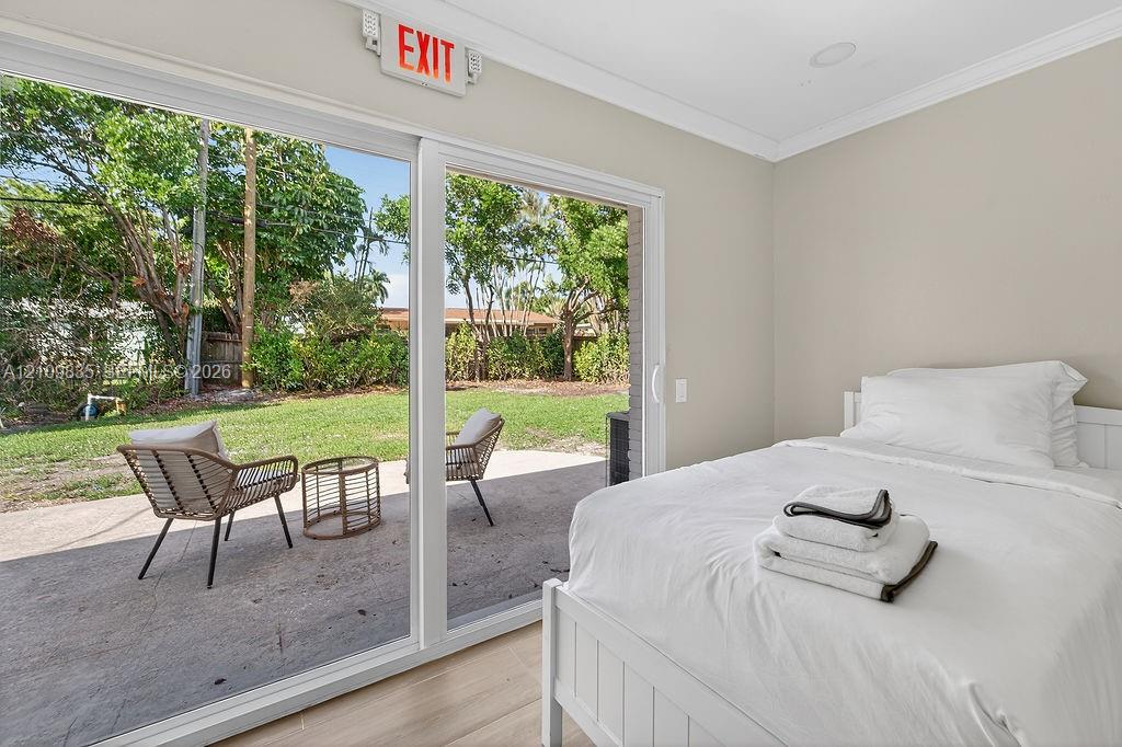 Large sliding glass doors opening to a concrete patio with mature landscaping, complemented by wood-finish flooring and recessed lighting