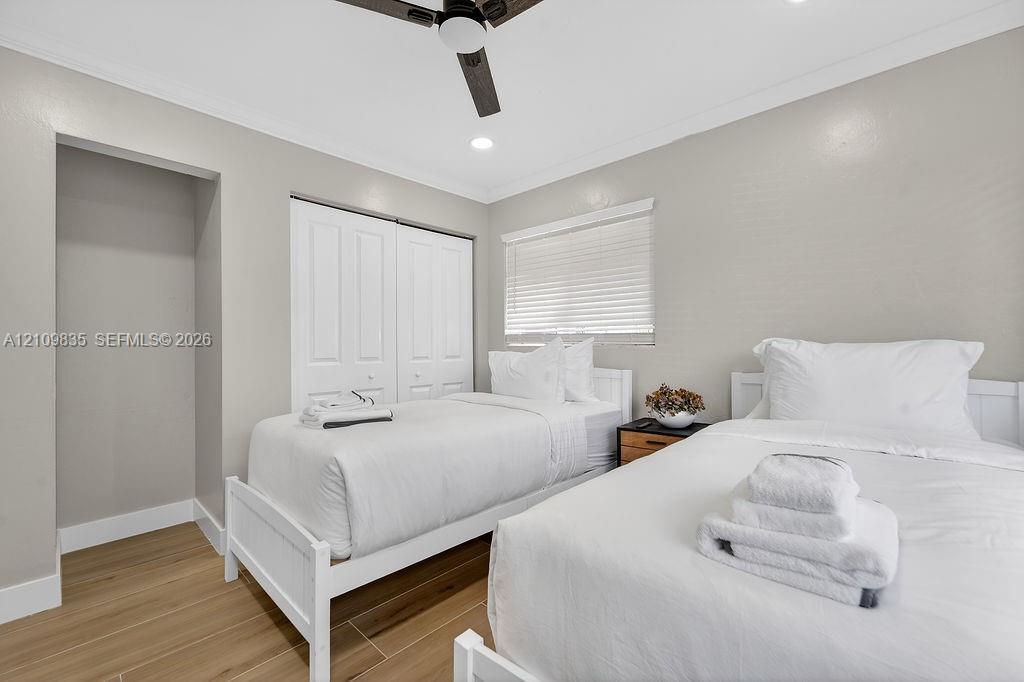 Room featuring wood-finish tile flooring, dual-panel closet doors, recessed lighting, ceiling fan with integrated lighting, and horizontal window blinds