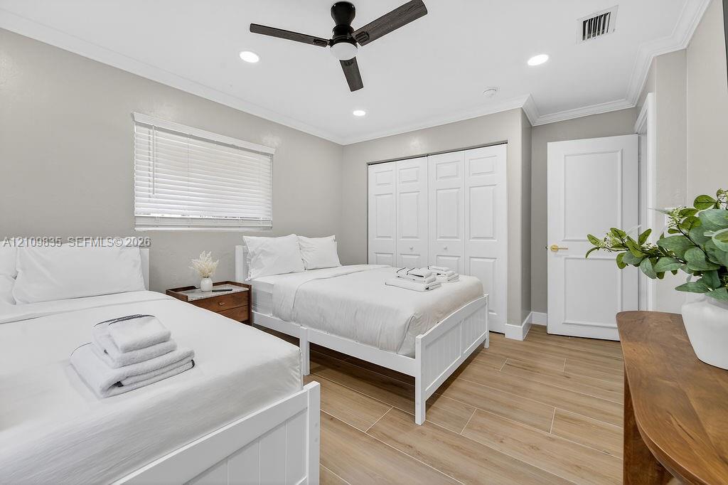 Neutral-toned room featuring wood-finish tile flooring, a matte black ceiling fan, recessed lighting, crown molding, and a multi-panel closet