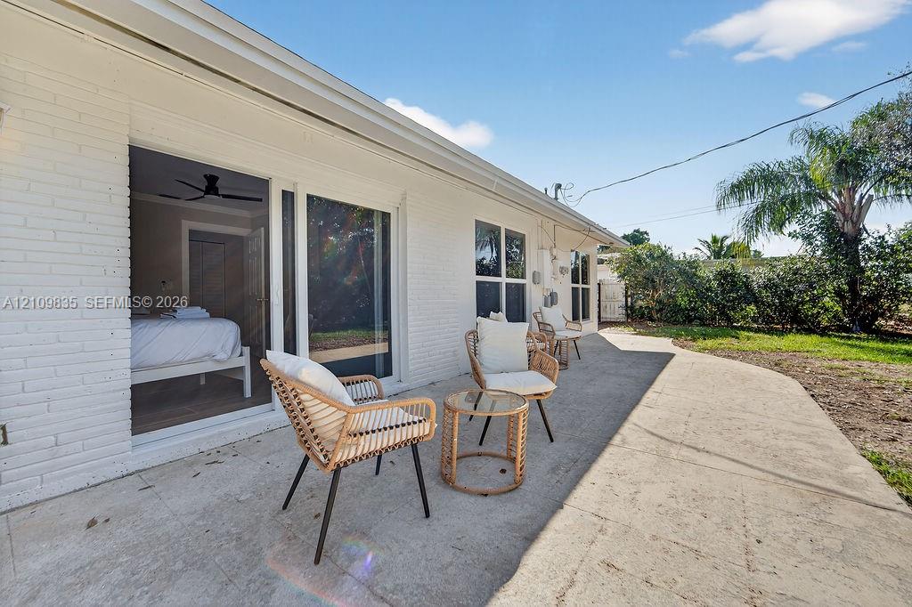 Painted brick exterior featuring a concrete patio, sliding glass door, and lawn area