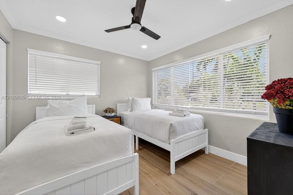 Neutral-toned room featuring wood-finish flooring, recessed lighting, a modern ceiling fan, and large windows with horizontal blinds