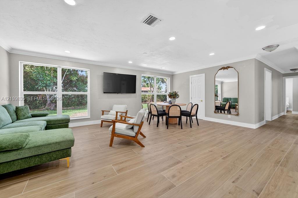 Open-concept interior featuring wood-finish tile flooring, recessed lighting, and large windows providing natural light
