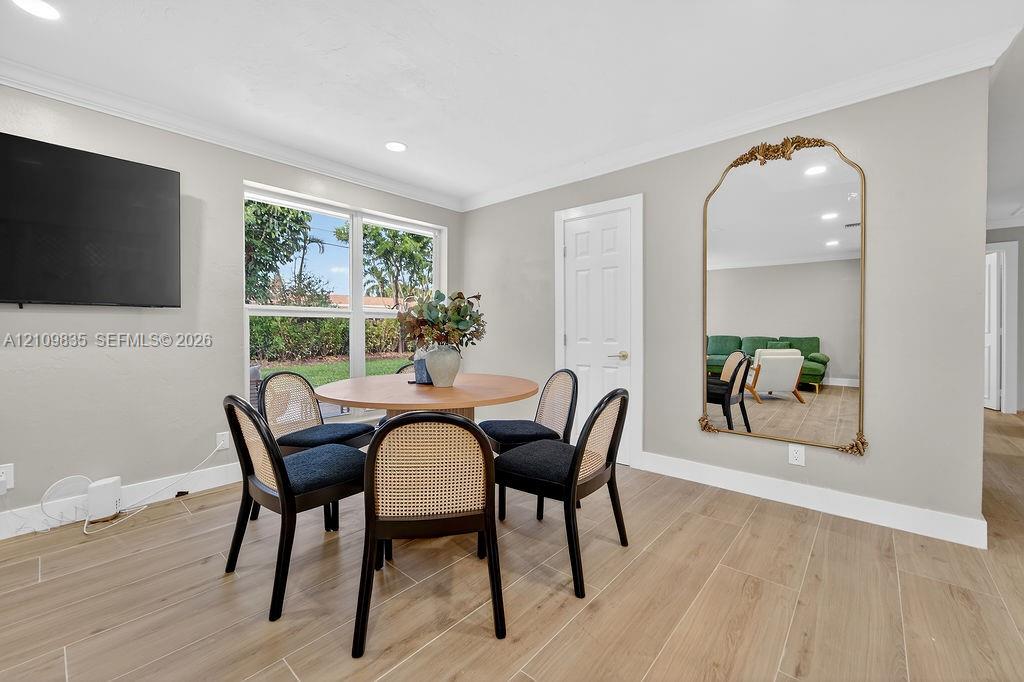 Neutral interior space featuring wood-finish tile flooring, recessed lighting, crown molding, and a large multi-pane window