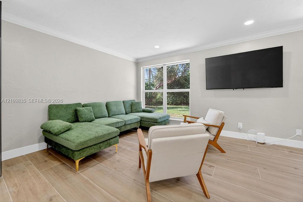Neutral-toned interior featuring wood-finish tile flooring, crown molding, recessed lighting, and large windows