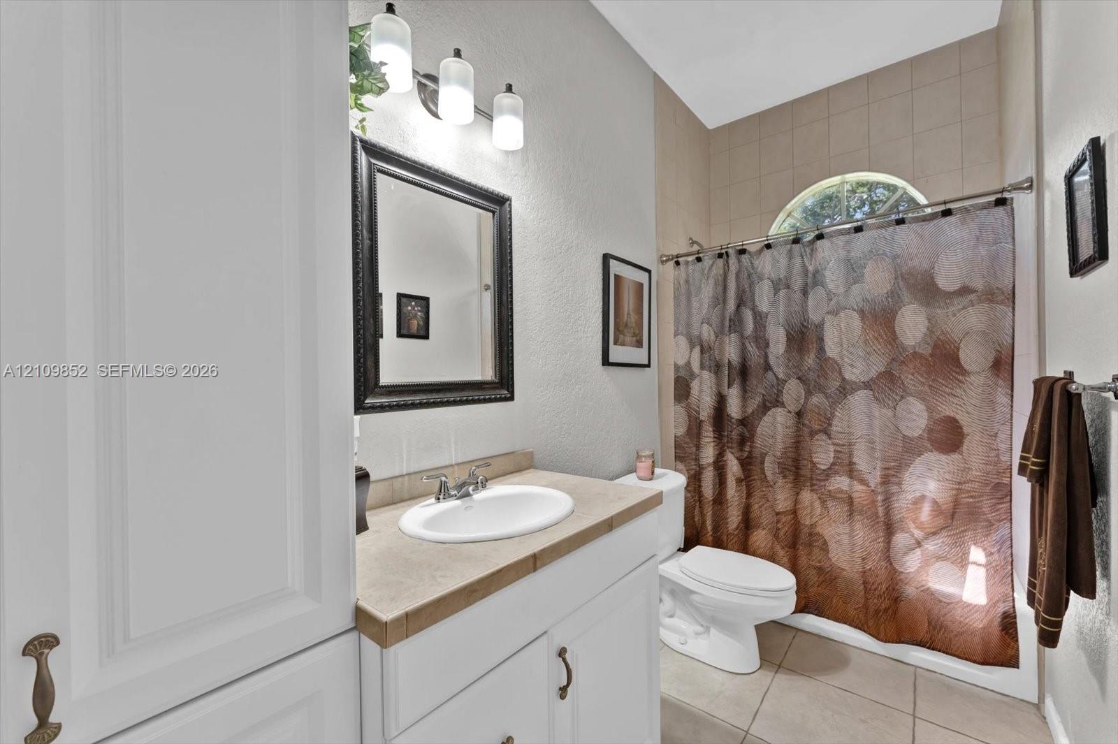 Hall bathroom featuring a shower-tub combination with a semi-circular transom window *