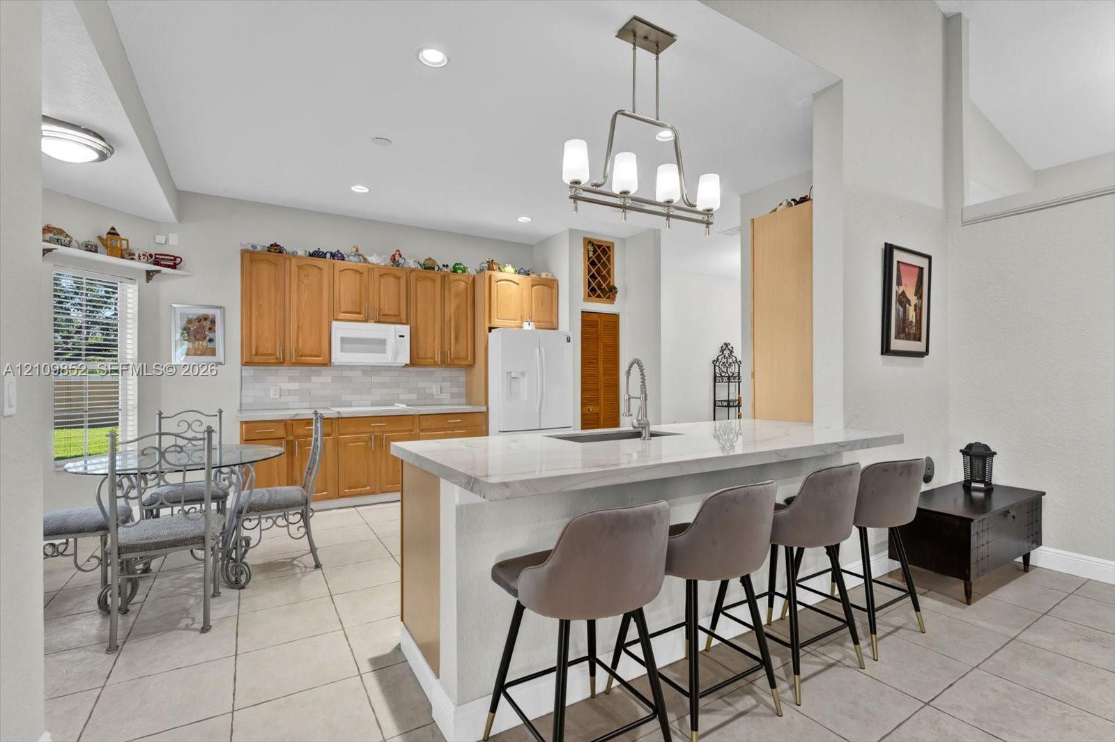 Kitchen featuring solid wood cabinetry, quarzite countertops, subway tiled backsplash, newer appliances , with the breakfast area off to the left *