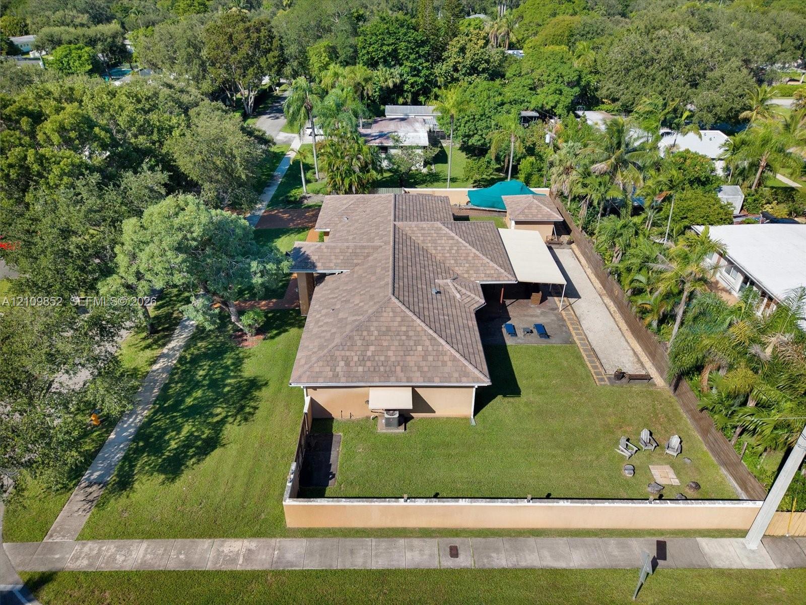 Aerial perspective of the home featuring a brand new 2026 concrete flat tiled roof, manicured lawn, concrete perimeter wall with lights and a covered patio *