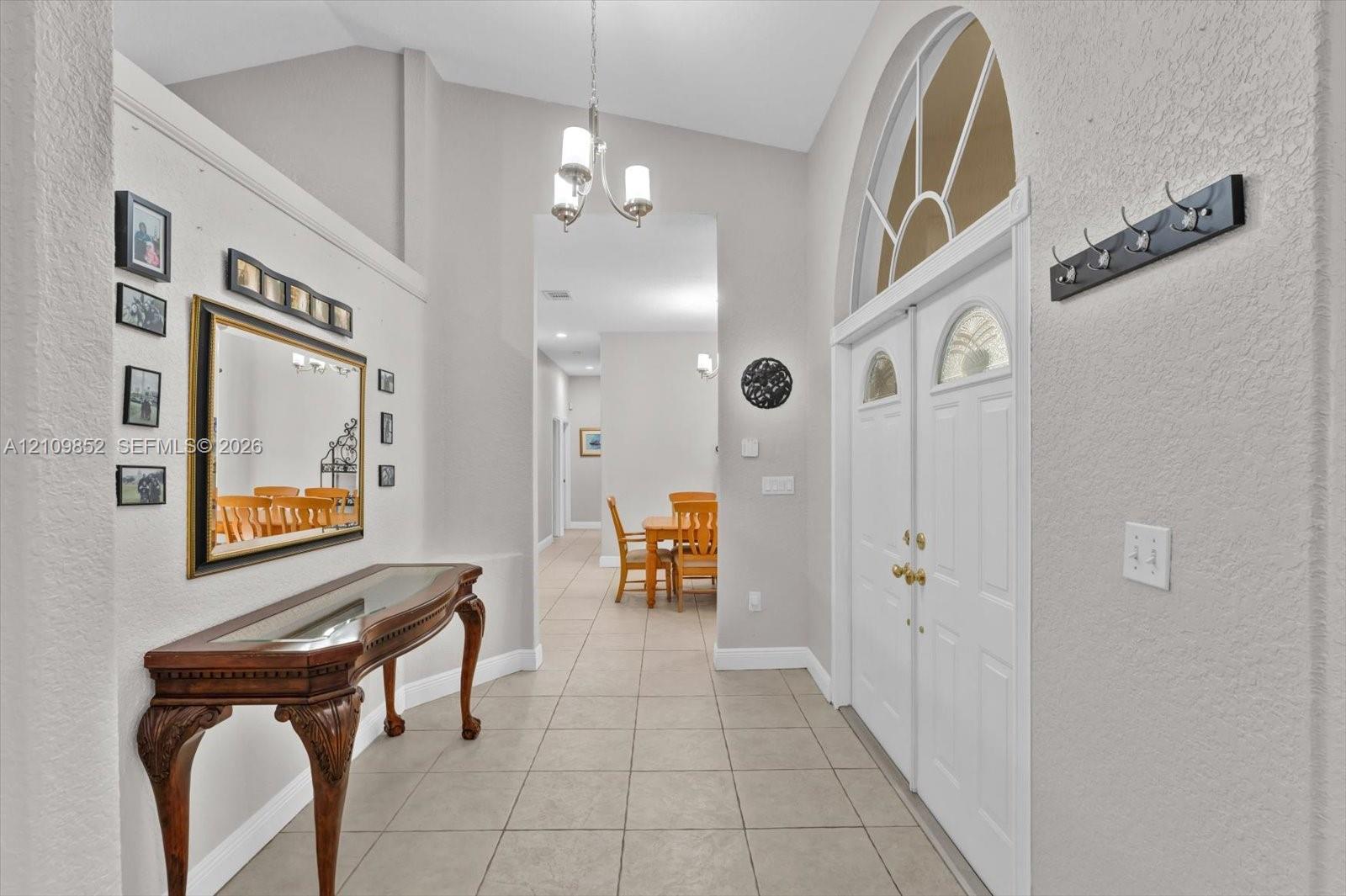 Formal foyer featuring volume ceilings, tile flooring, and a double-door entry with an arched transom window *