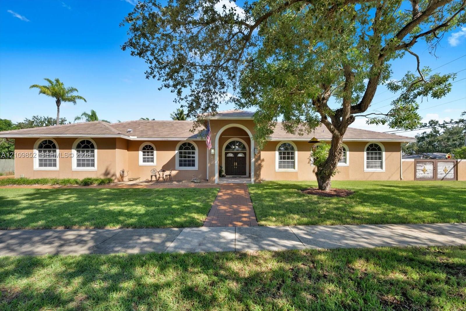 Single-story exterior featuring a stamped concrete walkway, arched entryway, and multiple arched windows * concrete wall in the front with custom metal gates *
