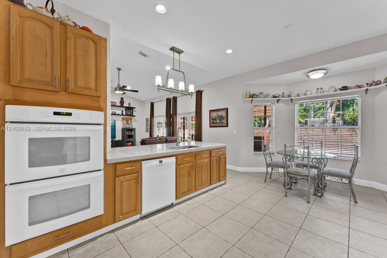 Kitchen featuring wooden cabinetry, white double wall oven, Bosch dishwasher, tile flooring, and a recessed window breakfast nook *