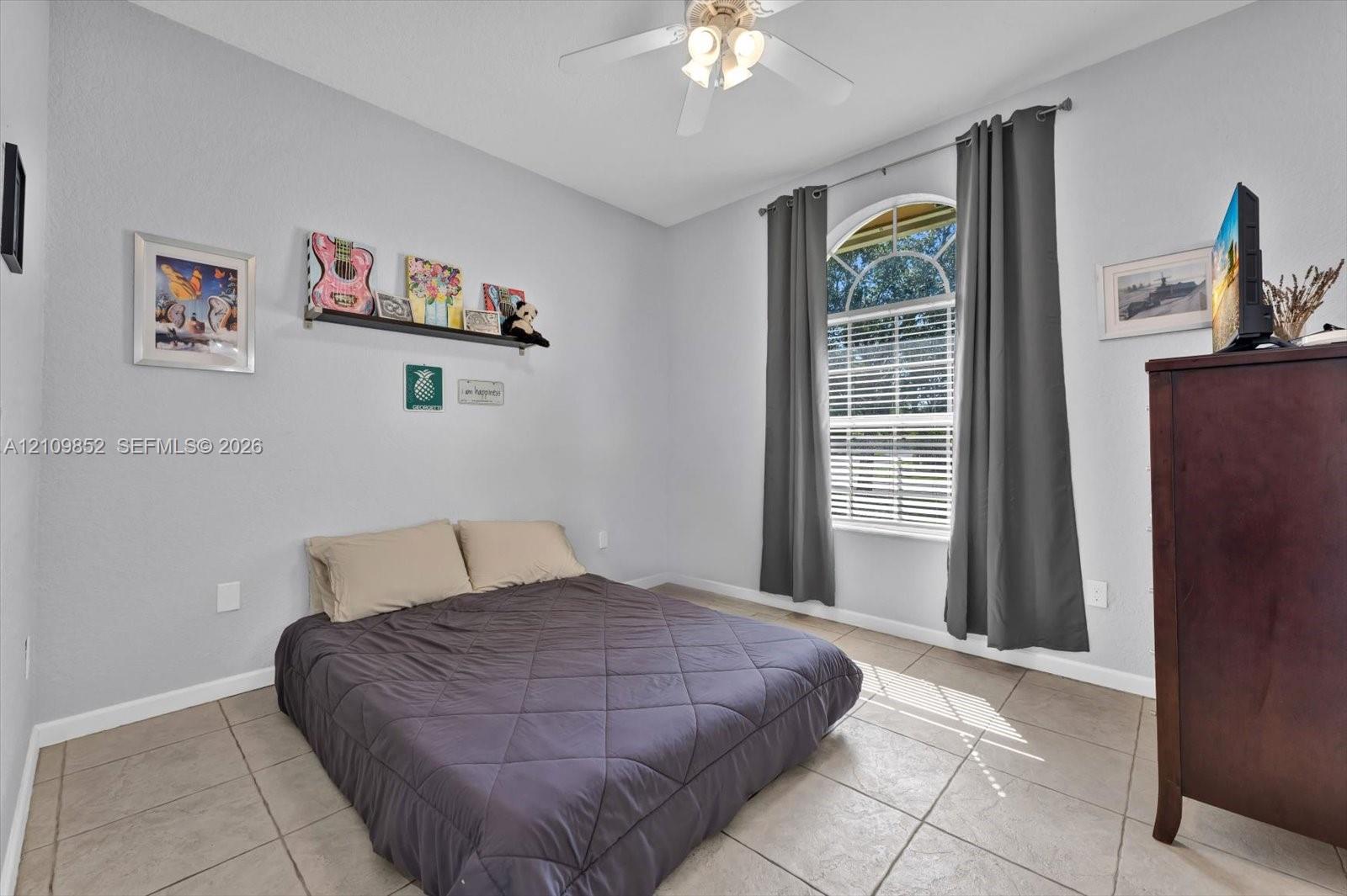 Southern facing bedroom with high celings and neutral-toned tile flooring and arched window *