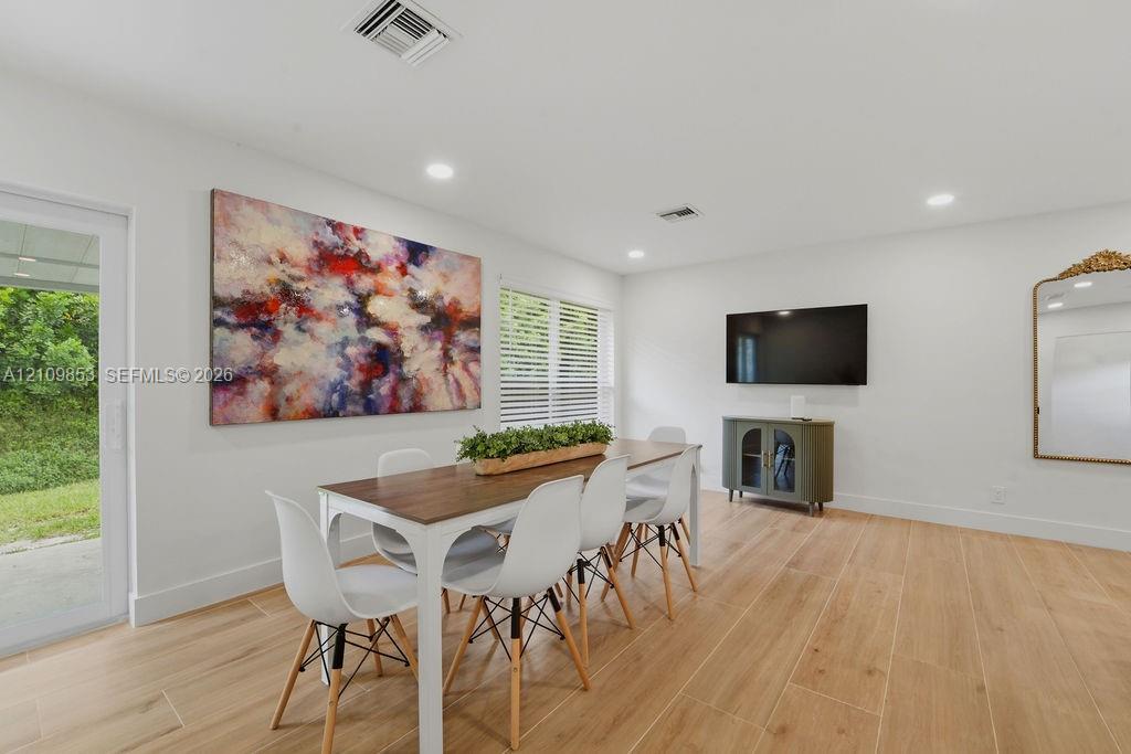 Wood-finish flooring, recessed lighting, and a glass-paneled sliding door providing access to the exterior