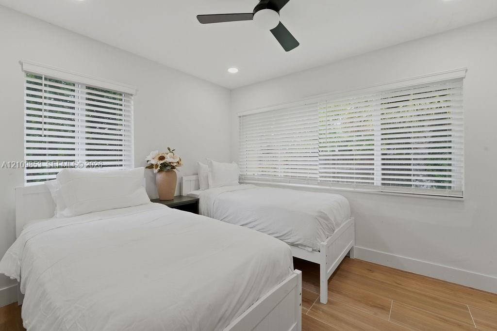Interior room featuring wood-finish flooring, recessed lighting, a matte black ceiling fan, and large windows with horizontal blinds