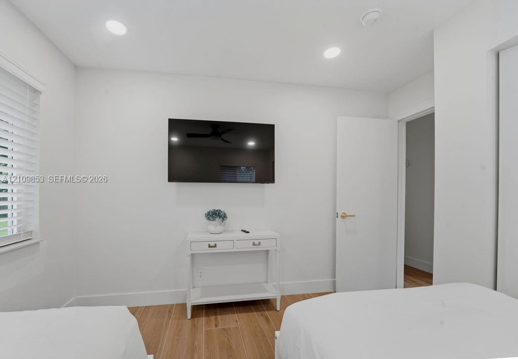 Room featuring wood-finish flooring, recessed lighting, and horizontal slatted window blinds
