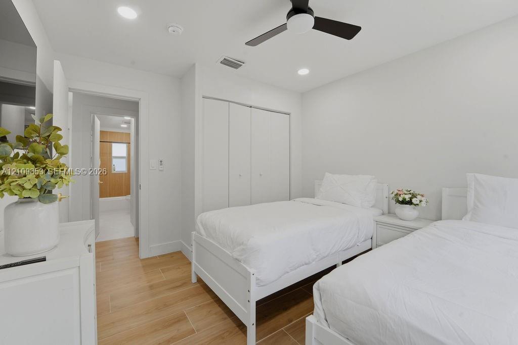 Wood-finish flooring, recessed lighting, matte black ceiling fan, and built-in closet with double-panel doors