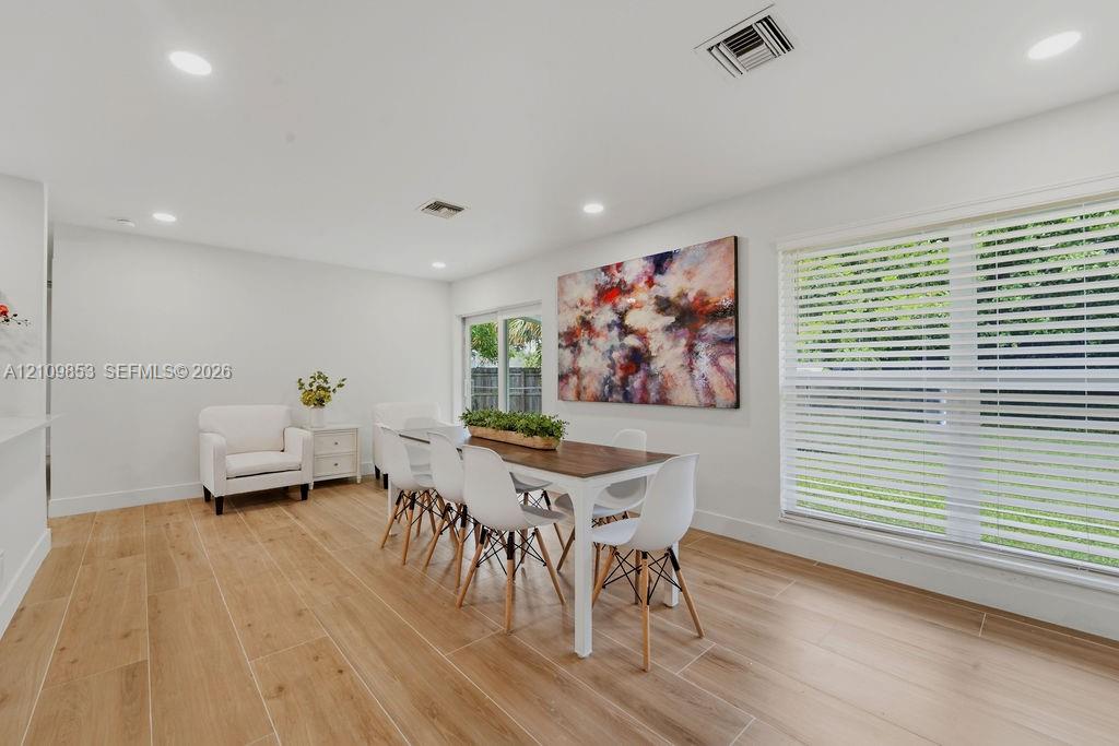 Neutral-toned interior featuring wood-finish tile flooring, recessed lighting, and large windows with horizontal blinds