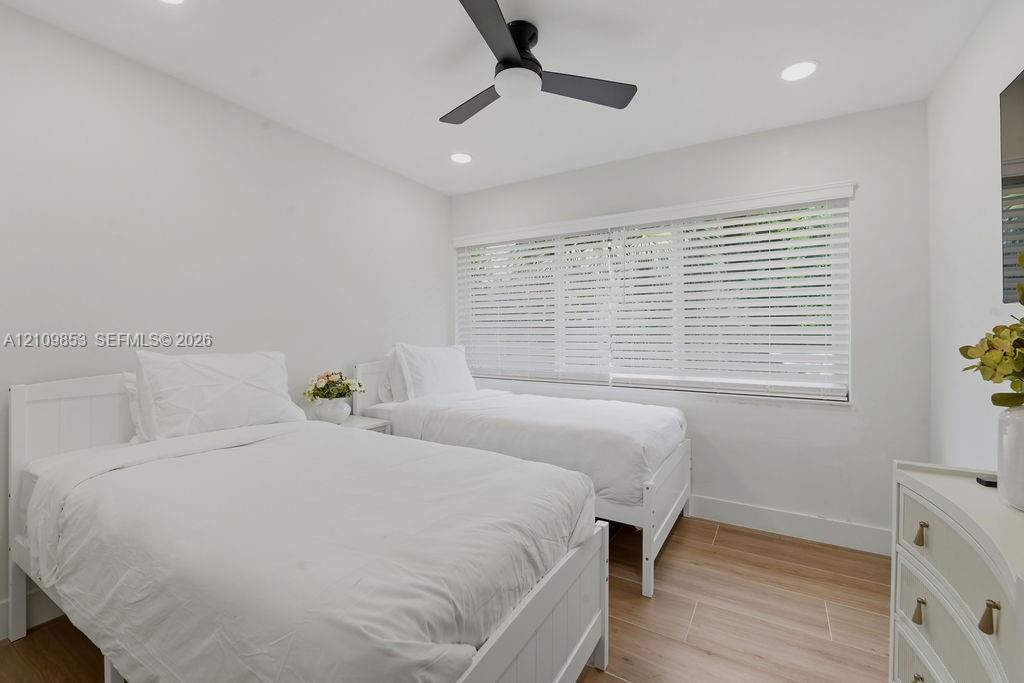 Wood-finish flooring, recessed lighting, matte black ceiling fan, and large windows with horizontal blinds