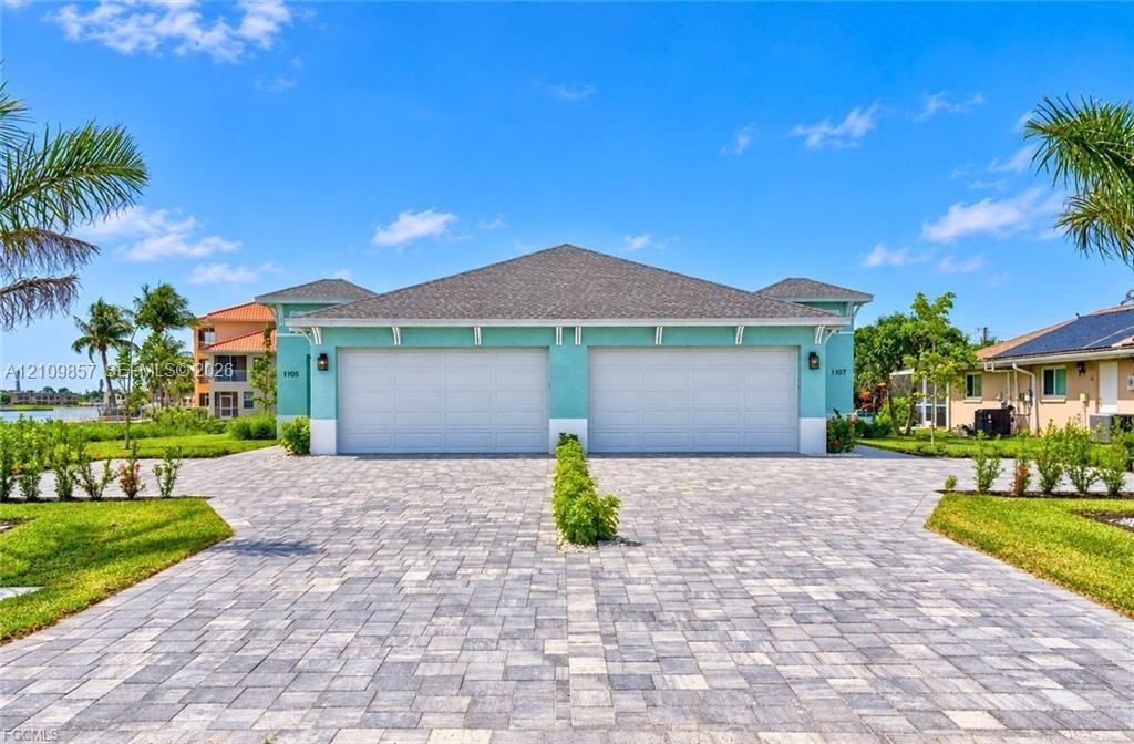 Exterior facade featuring dual garage doors, a stone-paver driveway, and professional landscaping Exterior facade featuring dual garage doors, a stone-paver driveway, and professional landscaping