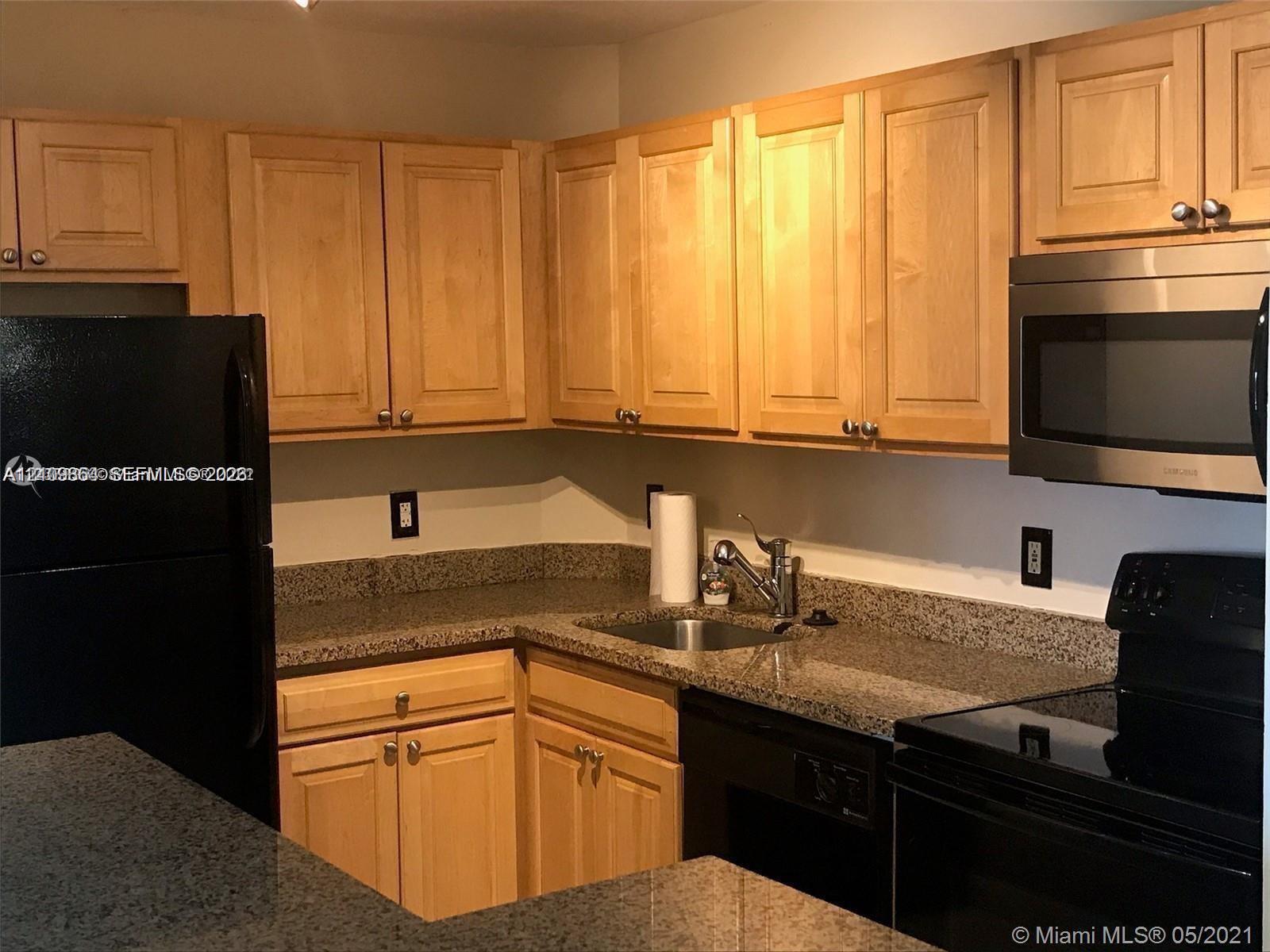 Kitchen featuring shaker-style wood cabinetry, stone countertops, stainless steel undermount sink, and integrated stainless steel microwave Kitchen featuring shaker-style wood cabinetry, stone countertops, stainless steel undermount sink, and integrated stainless steel microwave