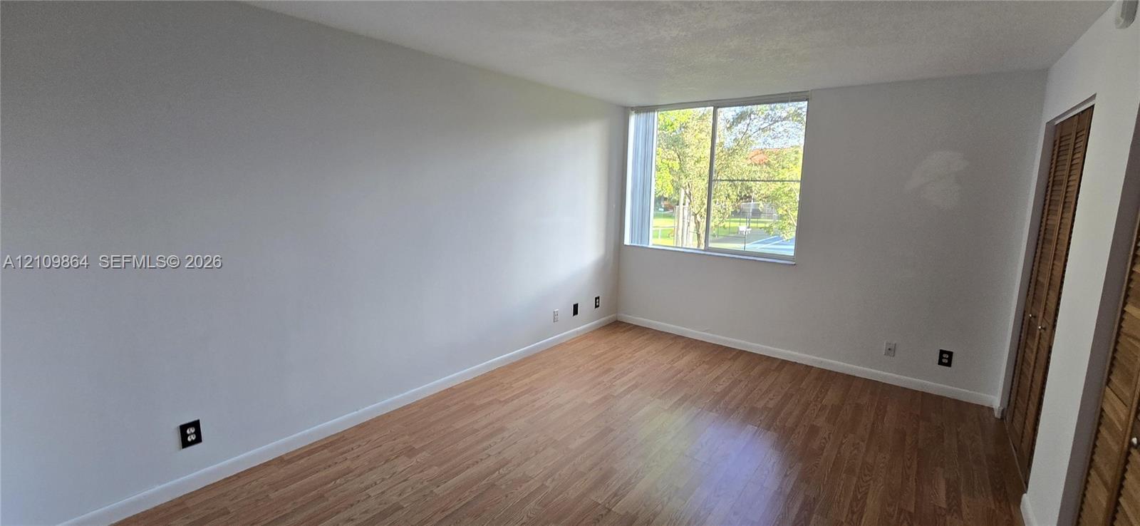 Interior space featuring wood-finish flooring, a large sliding window, and wooden bi-fold closet doors
