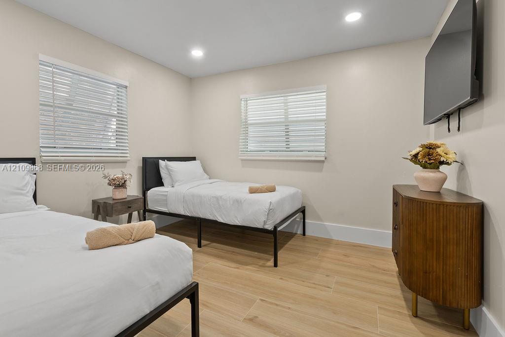 Interior room featuring wood-finish flooring, neutral walls, two horizontal windows with slatted blinds, and recessed lighting