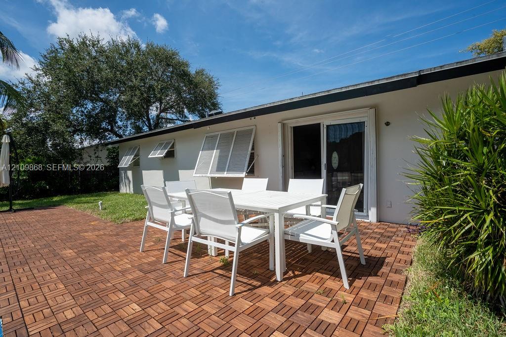 Exterior patio featuring patterned modular wood decking, sliding glass doors, and louvered storm shutters