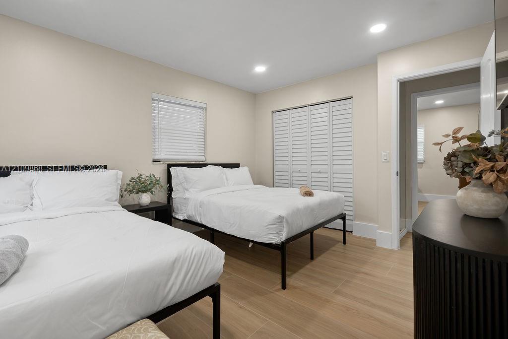 Wood-finish tile flooring, recessed ceiling lighting, and folding louvered closet doors