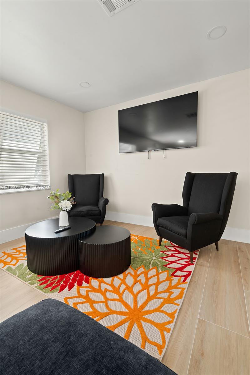 Room featuring wood-finish flooring, neutral wall paint, recessed lighting, and horizontal window blinds