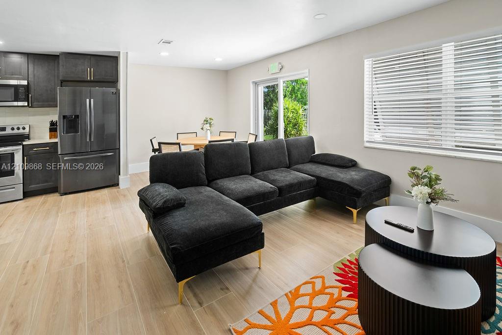 Open-concept living space featuring wood-finish flooring, dark cabinetry, recessed lighting, and a sliding glass door