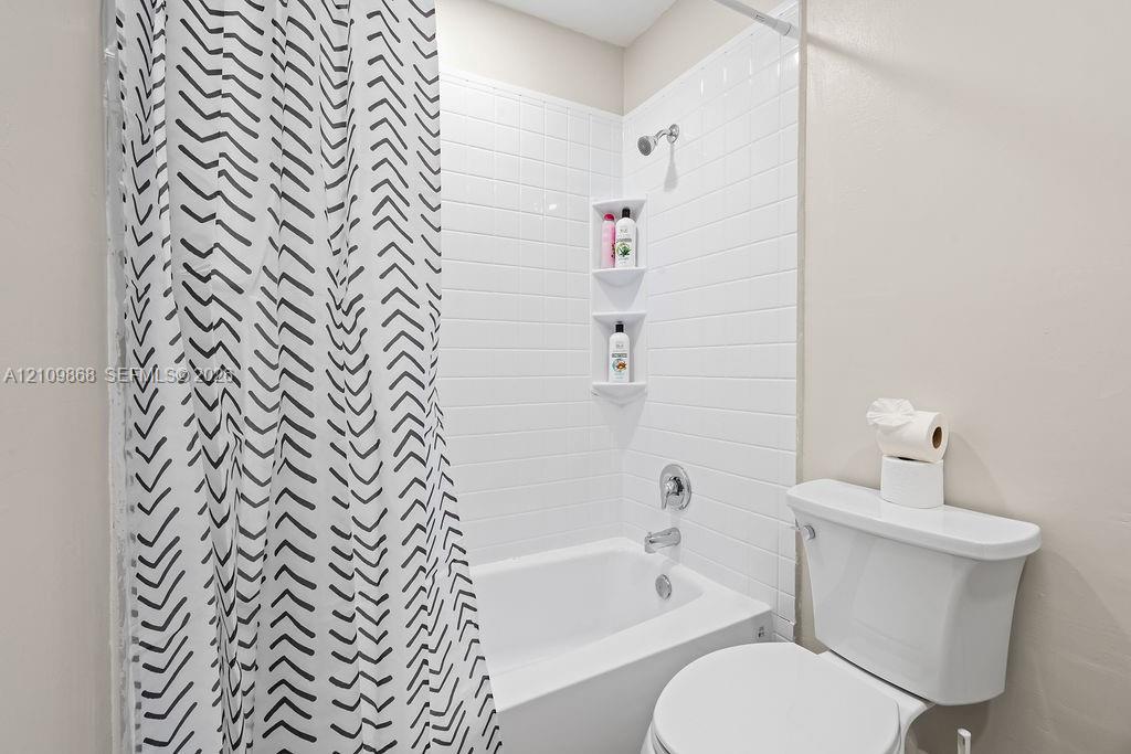 Bathtub with white subway tile surround, integrated dual shelving niches, and chrome fixtures