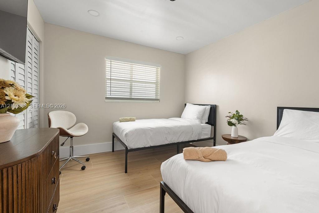 Neutral-toned interior featuring wood-finish flooring, recessed lighting, and white plantation-style shutters