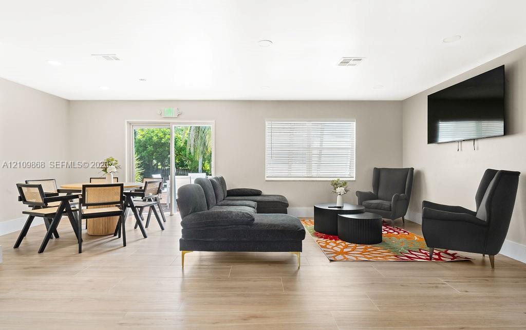 Open-concept interior featuring wood-finish tile flooring, neutral wall paint, recessed lighting, and a sliding glass door providing exterior exposure