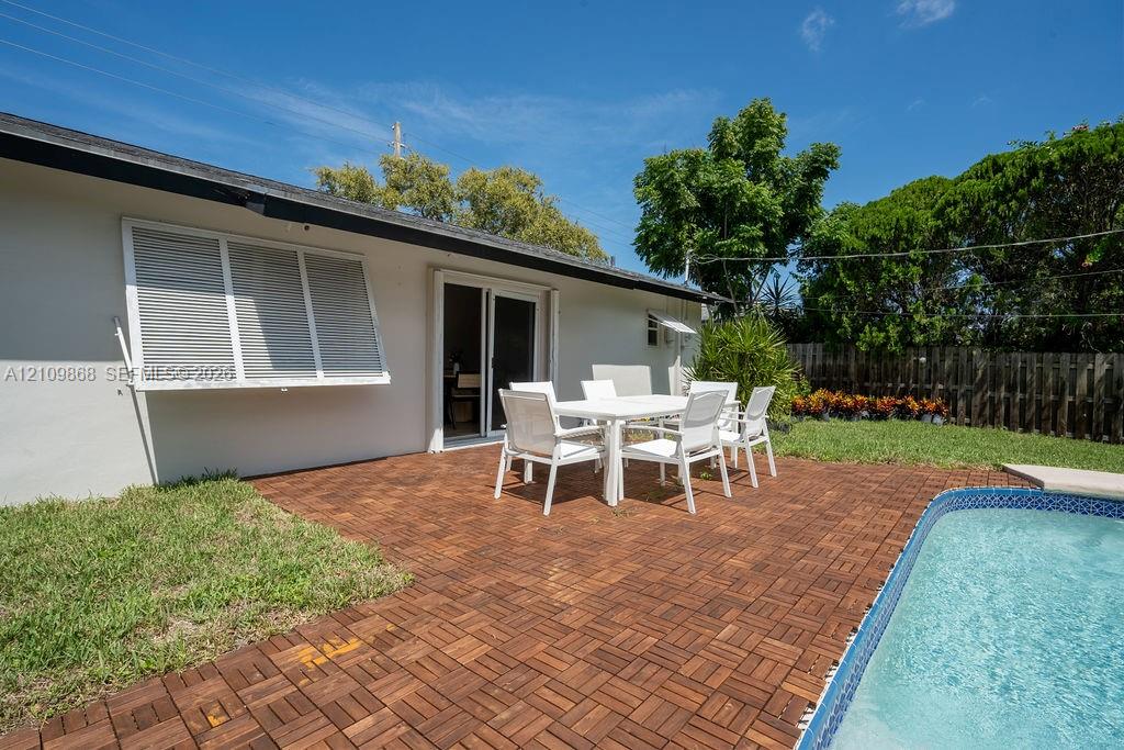 Backyard featuring a swimming pool, wood-finish deck tiling, a manicured lawn, and horizontal exterior window shutters