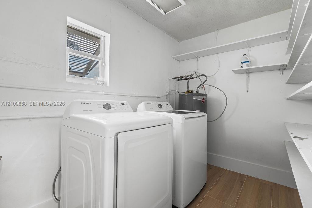 Utility space featuring wood-finish flooring, white wall-mounted shelving, and a singular window