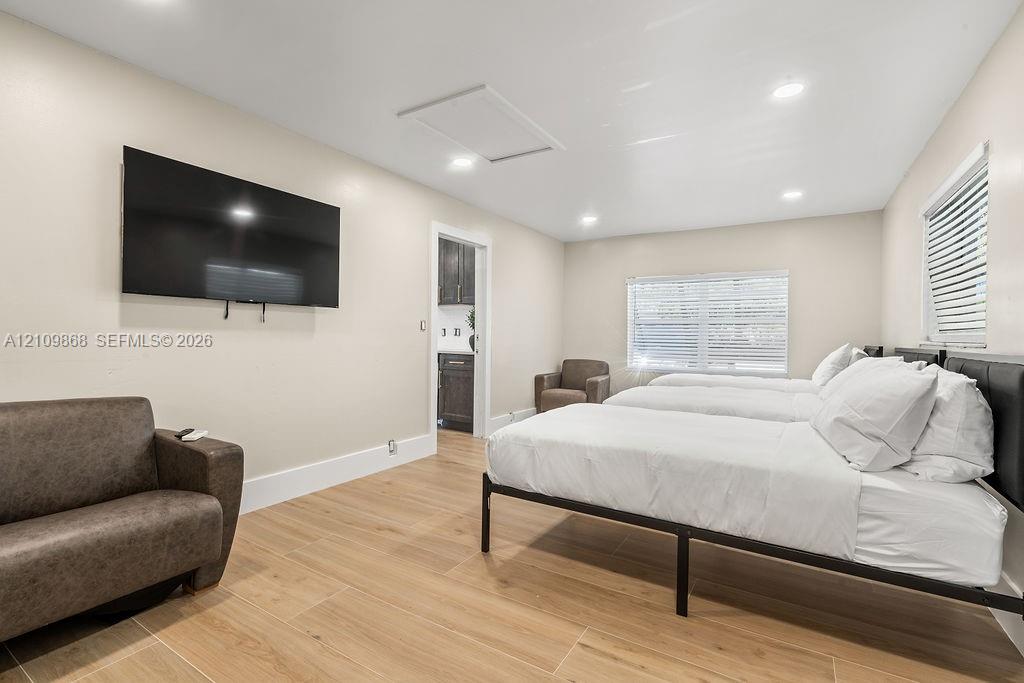 Neutral-toned interior featuring wood-finish flooring, recessed lighting, and windows equipped with horizontal blinds