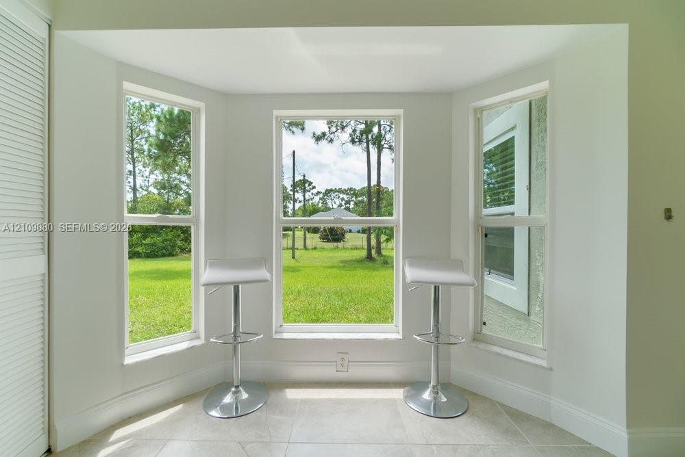 Bay window with triple-pane windows, neutral stone-finish tile flooring, and white louvered closet doors