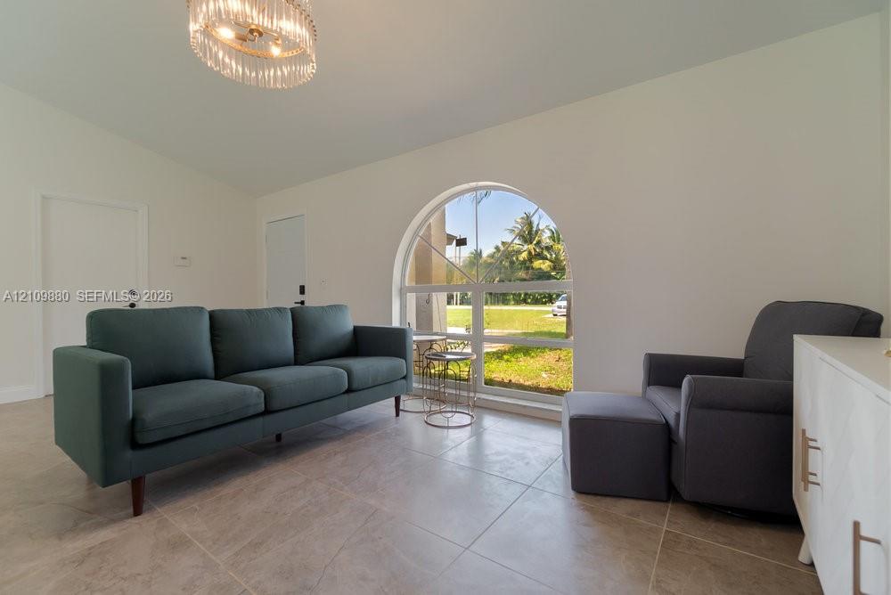 Vaulted ceilings, oversized arched window, large-format tile flooring, and a crystal tiered chandelier