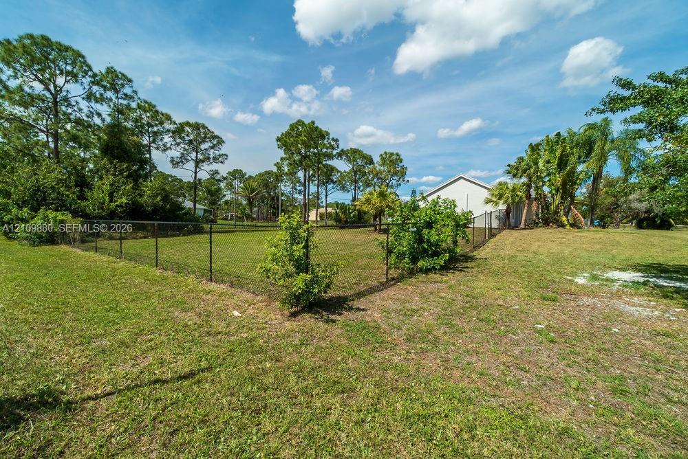 Fenced yard featuring a level lawn, mature shade trees, and perimeter landscaping