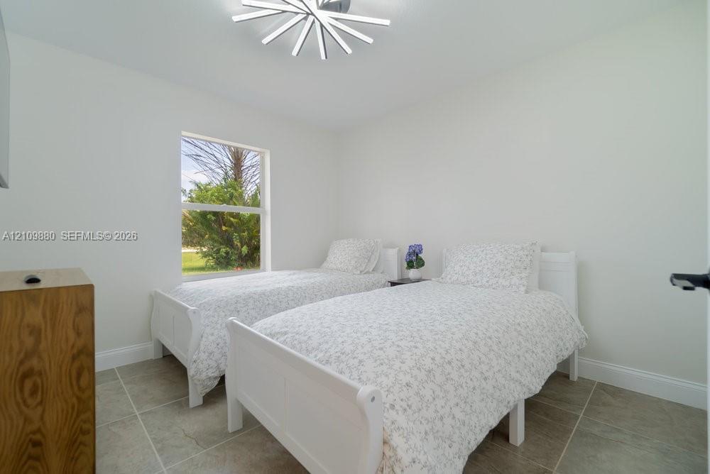 Neutral-toned room featuring large-format ceramic tile flooring, a geometric LED ceiling fixture, and a single-pane window